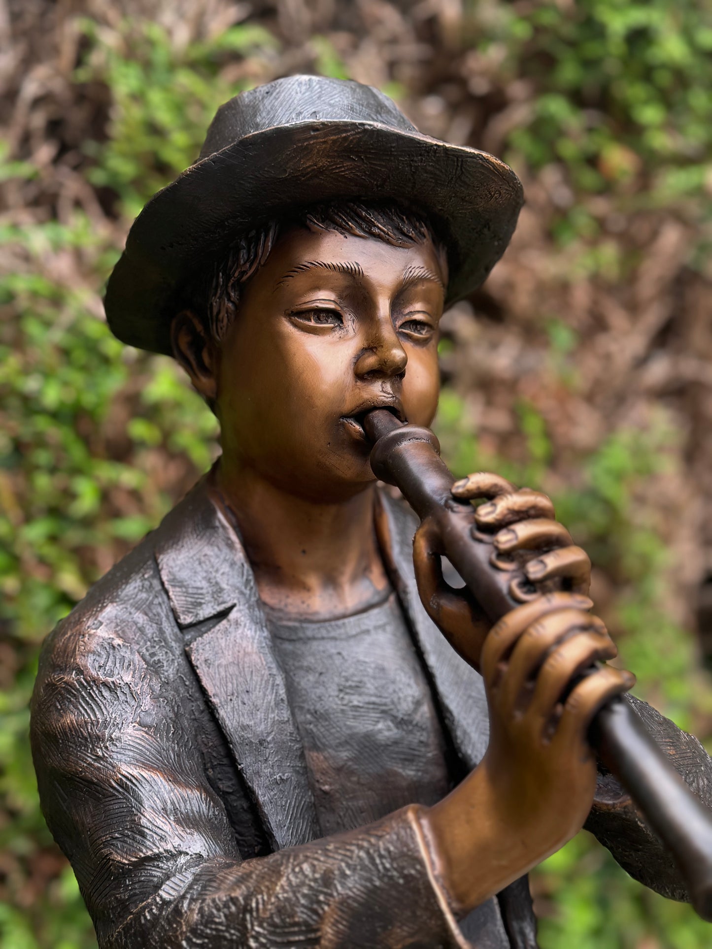 Estátua de bronze de menino com flauta.