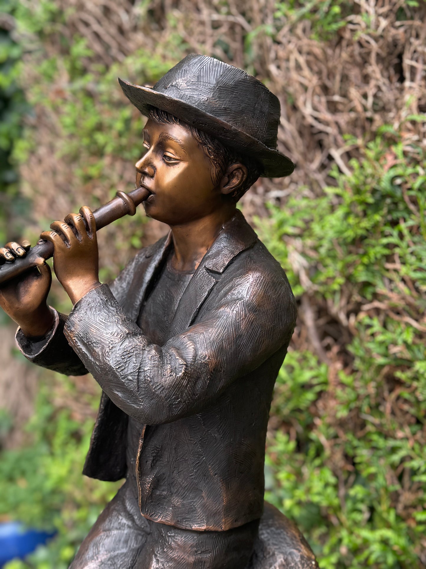 Estátua de bronze de menino com flauta.