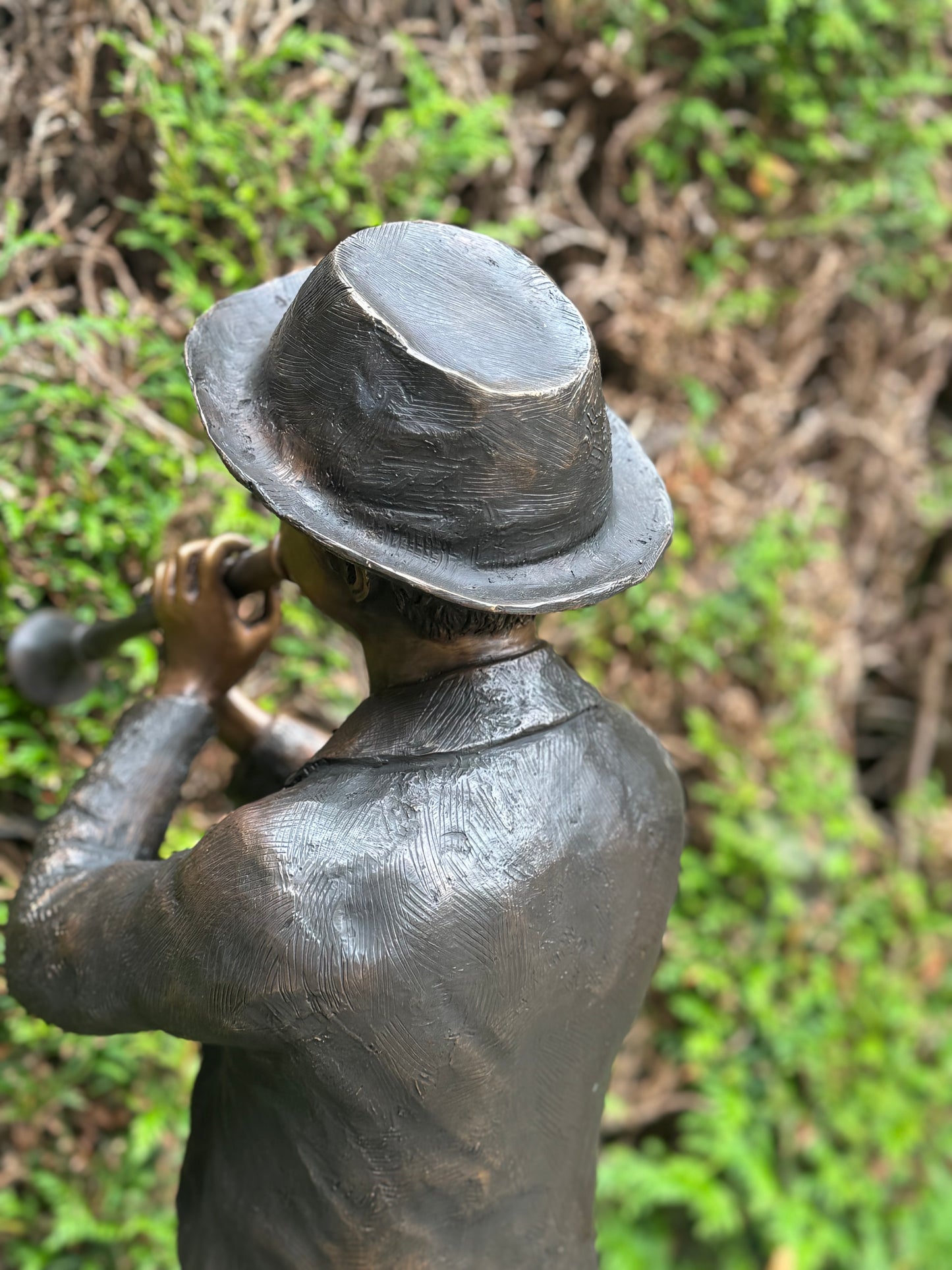 Estátua de bronze de menino com flauta.